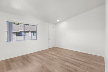 Spacious modern living room interior featuring wood-style flooring, large windows, and natural lighting. Ideal for real estate marketing, rental listings, and interior design content.