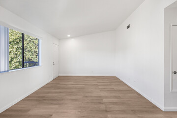 Spacious modern living room interior featuring wood-style flooring, large windows, and natural lighting. Ideal for real estate marketing, rental listings, and interior design content.