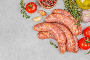 Raw butchers sausages with spices and vegetables on a light background, top view. copy space