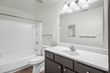 Bright modern bathroom interior with white bathtub, single sink vanity, and granite countertop. Perfect for real estate, interior design, and home improvement concepts.