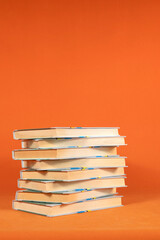 Books are stacked one on top of the other on an orange background