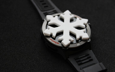 Snowflake Lies on a Black Display of Smart Watch. Photo for Theme of Winter Season is Over 
