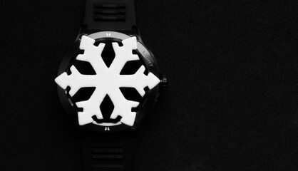 White Snowflake Model on Black Turned Off Digital Watch in Darkness. Seasonal Time Conceptual Image...