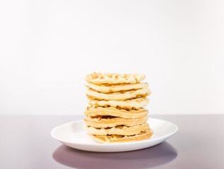 many delicious waffles on a plate for breakfast on a light background