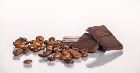 slices of delicious dark chocolate and coffee beans close up on a light background.