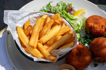 Lunch in cafe with vegetarian cheese and green asparagus croquettes served with fresh salad and french fries potato in Bruges, Belgium
