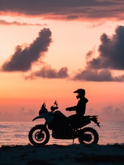 Fototapeta premium Silhouette of motorcyclist on beach during vibrant sunset over ocean horizon.
