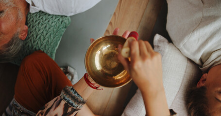 Tibetan bowl, healing and hands of person in studio for wellness retreat, relax and meditation. Chakra balance, peace and sound therapy with above of shaman for energy, holistic ritual and closeup