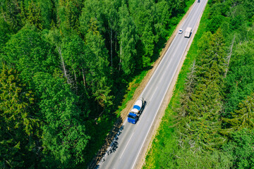 Aerial drone view of green summer woods and asphalt road with cars and concrete mixer truck