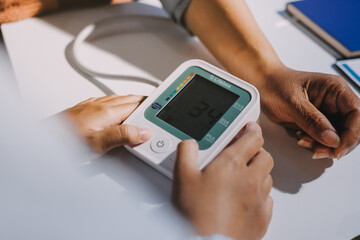 Nurse measuring blood pressure of elderly woman at table, closeup. Assisting senior generation