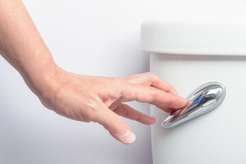 Female hand pressing the toilet handle in a bathroom