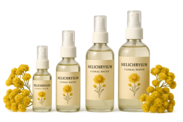 Bottles of Helichrysum floral water in various sizes, surrounded by yellow Helichrysum flowers. Concept Floral Water Bottles, Helichrysum Essence, Natural Skincare, Aromatic Beauty