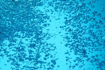 Many water bubbles on light blue background, closeup