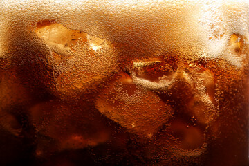 Refreshing cola with ice as background, macro view
