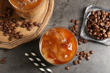 Tasty iced coffee and beans on grey table, flat lay