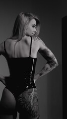 Blonde with a beautiful figure in a black patent leather bodysuit posing in a studio. Studio...