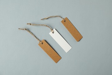 Blank tags with strings on grey background, flat lay