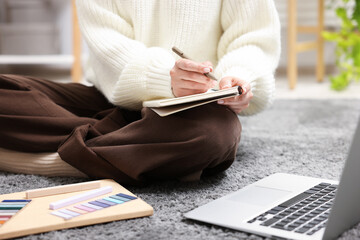 Woman with planner and laptop on floor indoors, closeup