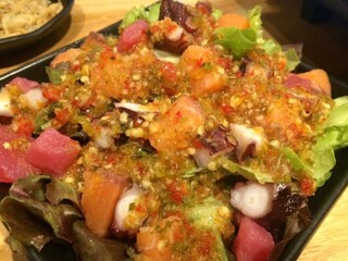 Thai spicy mixed salad, salmon, tuna, octopus , seafood mixed vegetable and herb in black plate