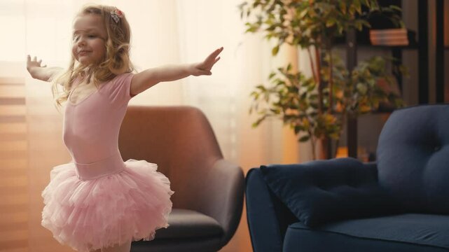Little girl in pink ballet tutu doing cartwheel at home, practicing acrobatics