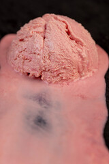 melting pink ice cream on a black board, sweet cold pink ice cream with strawberry flavor, close up