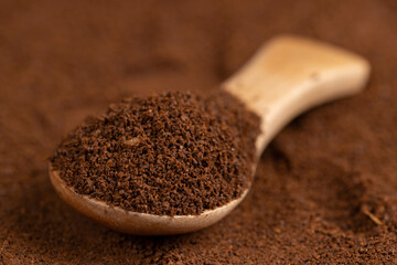 ground coffee and a wooden spoon, a large number of roasted ground coffee beans in powder and a wooden spoon