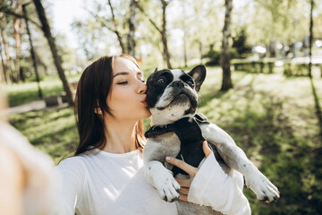 girl taking selfie with french bulldog. girl and dog walking in park