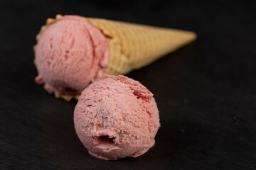 sweet cold pink ice cream with strawberry flavor, ice cream in a waffle cone, close up