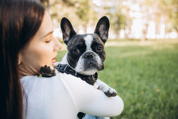 girl holding french bulldog in her arms. girl kissing and having fun with her dog