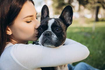 girl holding french bulldog in her arms. girl kissing and having fun with her dog