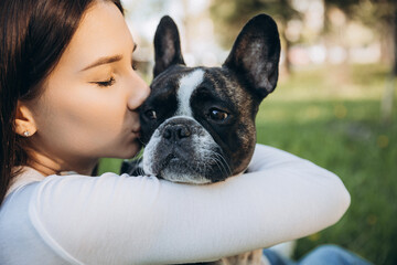girl holding french bulldog in her arms. girl kissing and having fun with her dog