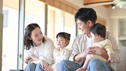 家の自宅のソファーでくつろぐ4人の幸せ日本人家族のみんなで笑顔の子育てイメージのスロー動画