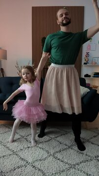 Funny father and little daughter in skirts recording dance video on phone