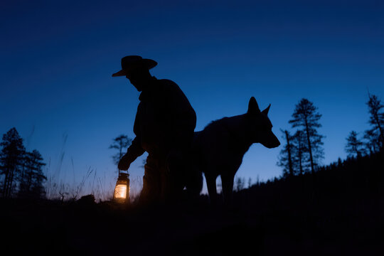 Cowboy holding lantern with dog in twilight forest silhouette - Powered by Adobe