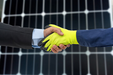 Engineer and customer shaking hands after successful installation of solar panels on a house roof,...