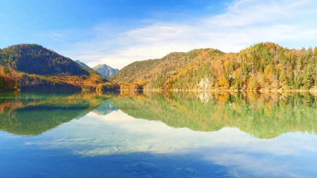 Calm waters reflecting autumn leaves and blue sky near Schwangau in the picturesque Ostallg&auml;u region