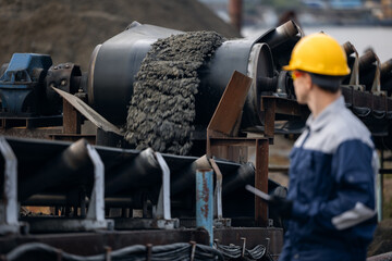 Male engineer surveying ore mining operations in sand quarry with tablet computer