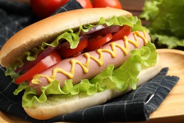 Tasty hot dog with tomato, onion, lettuce and mustard on table, closeup