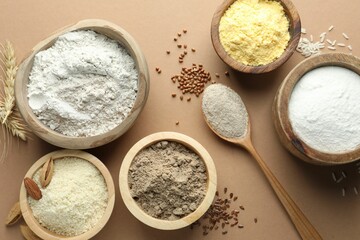 Different types of flour on light brown table, flat lay