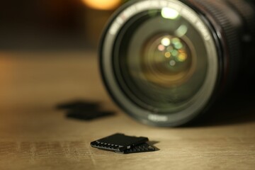 SD memory cards and photo camera on wooden table, closeup