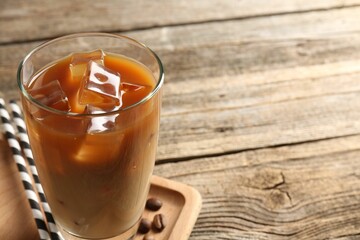 Tasty iced coffee and beans on wooden table, closeup. Space for text