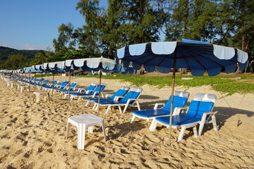 Relaxing Beach Setup with Blue Sun Loungers and Umbrellas on Sandy Shoreline