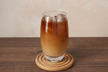 Tasty iced coffee in glass on wooden table