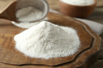 Wheat flour and spoon on wooden table, closeup