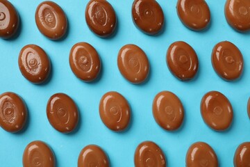 Many tasty caramel candies on light blue background, flat lay