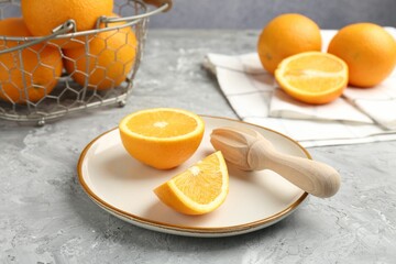 Wooden juicer and fresh oranges on grey table, closeup
