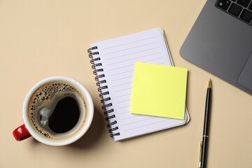 Notebook, sticky note, pen, coffee and laptop on beige background, flat lay
