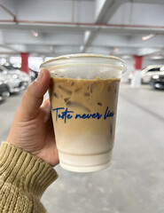 Hand Holding Iced Coffee in Parking Garage