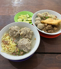 Two Bowls of Indonesian Meatball Noodle Soup with Lime Wedges