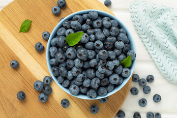 Bowl with fresh bright blueberries on wooden background,top view